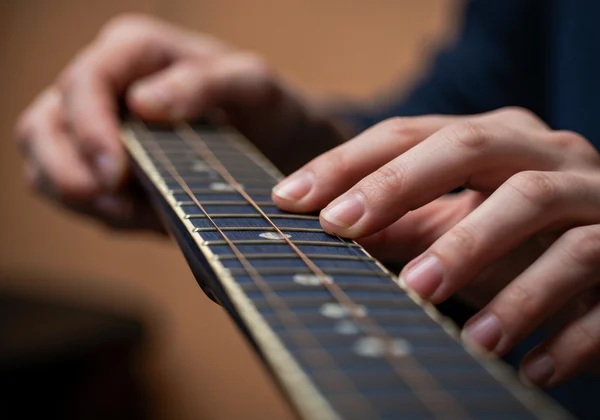 Close-up of hands stretching a guitar string after setup.